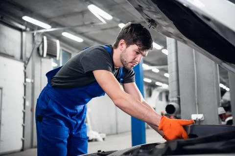 Workman inspects the engine under the car hood Stock Photos