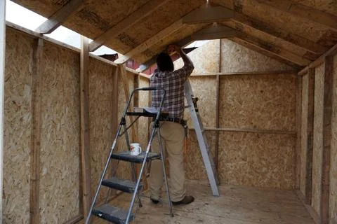 Workman installing interior of shed Stock Photos
