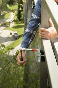 A workman installs a cable duct on a bridge railing high on a viaduct. Close Stock Photos