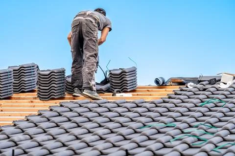Workman installs a fired ceramic tile on the roof of family house 스톡 사진