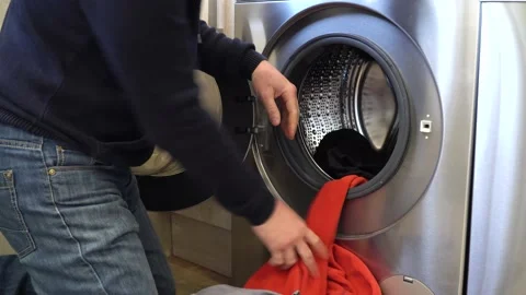 Workman loads the washing machine for the wash. Washes work clothes. Non-staged Stock Footage 149576499