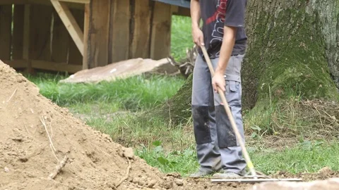 Workman raking ground Stock Footage
