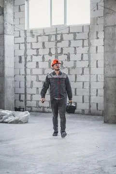 Workman ready for renovation work. Builder in uniform carrying toolbox at Stock Photos