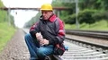 Workman sits on branch railway and drinks water from bottle HD Footage