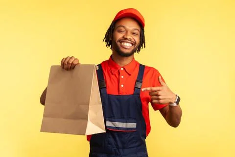 Workman in uniform pointing at ordered parcel, delivering food in paper package 스톡 사진