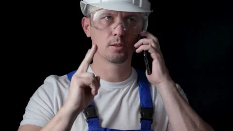 Workman using cellphone, black background Stock Footage 239343812