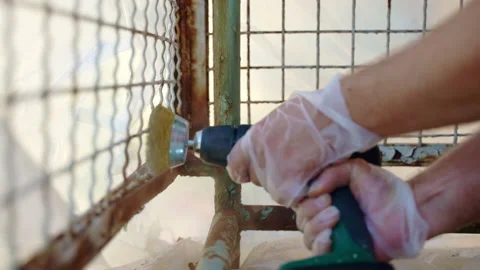 Workman using electrical grinder with metal brush nozzle for removing heavy Stockbeeldmateriaal 226841621