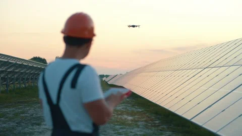 Workman using remote control to operate flying drone monitoring solar array Stock Footage 139018707