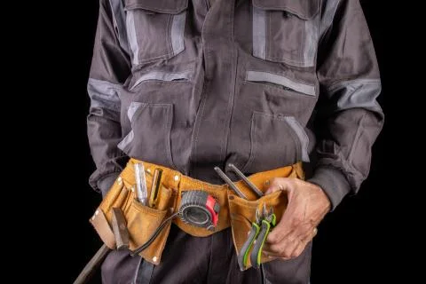Workman in work clothes and tool belt. Production worker with a drill in his  Stock Photos