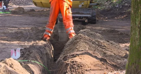 Workmen close a cable slot using a tamping rammer machine Stock Footage 106076241