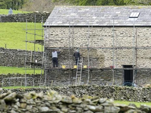 Workmen mortering a barn conversion in Austwick, Yorkshire Dales, UK. Foto stock