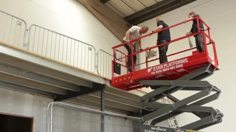 Workmen operate lifting platform in construction site Stockbeeldmateriaal 63146433