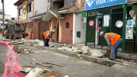 Workmen rolling large debris of heavy concrete from demolished sidewalk using Stock Footage 160376844