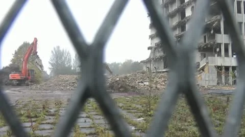Workmen use a grabber to break up rubble, shot through security fence Stock Footage 14781140