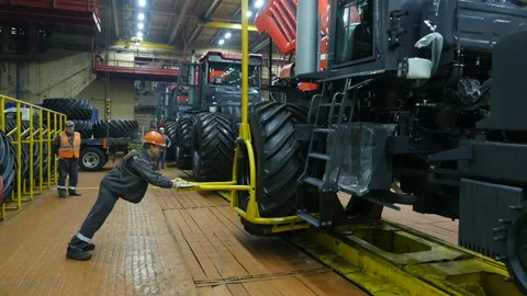 Workmen working on a factory.  Assembly line worker with large tire Stockbeeldmateriaal 110005271