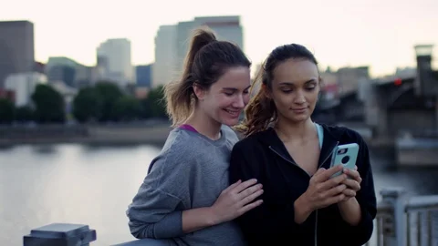 Workout Buddies Look Through Selfies Together On Smartphone, Beautiful City View Stock Footage 96012927