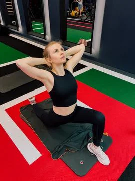 Workout in gym captured during stretch, workout shows athletic woman in action Stock Photos