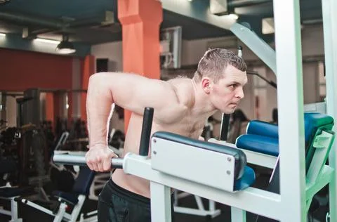 Workout. Muscular man doing push-ups on uneven bars in crossfit gym. Lifestyl 库存照片