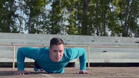 Workout. Young athlete performs push-ups in the morning in a stadium Stock Footage 84492819