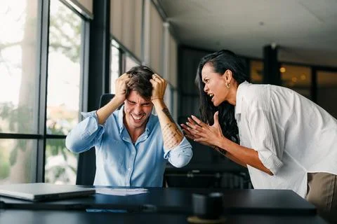 Workplace aggression, stressful work environment. Angry boss shouting at the Stock Photos