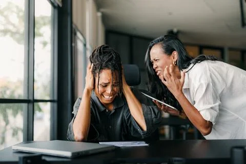 Workplace aggression, stressful work environment. Angry boss shouting at the Stock Photos