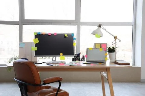 Workplace with blank laptop, computer and sticky notes in light office Stock Photos