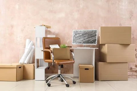 Workplace with computer and cardboard boxes near grunge wall in office on mov Stock Photos