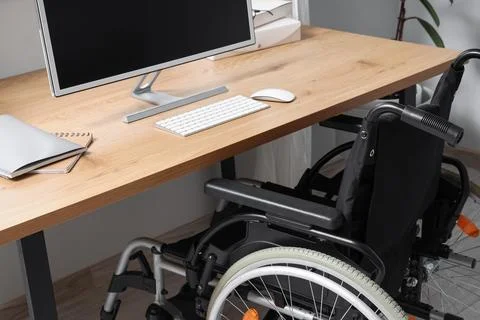 Workplace with computer and wheelchair in office Stock Photos