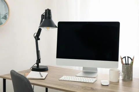 Workplace with computer, cup and lamp on wooden table. White background Stock Photos