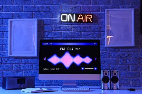 Workplace with computer, glowing ON AIR sign and blank frames in dark radio s Stock Photos