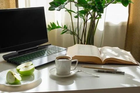 A workplace with a computer, an open book, an apple and a cup of coffee. Stock Photos