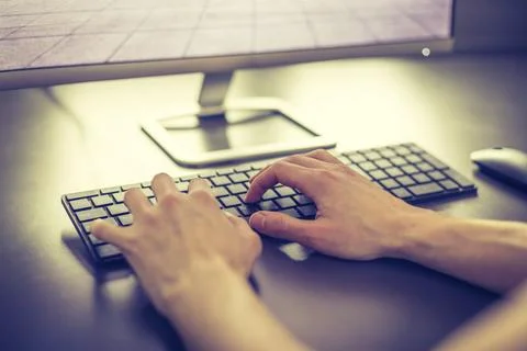Workplace of a freelancer: Arrangement of computer, keyboard and typing hands Stock Photos