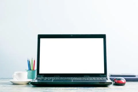 Workplace with laptop screen mockup, smartphone, notebook, coffee cup, pens a Stock Photos