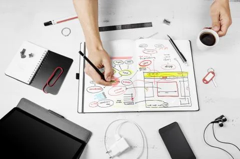 Workplace. Man working on notepad with hand drawn website projec Stock Photos