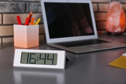 Workplace with modern digital clock and laptop in office. Space for text Stock Photos
