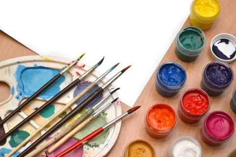 Workplace painter, brush in hand, jars with gouache, canvas for painting Stock Photos