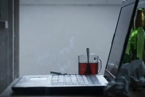Workplace of a programmer or writer. The laptop is on the table with tea, beer Stock-Fotos