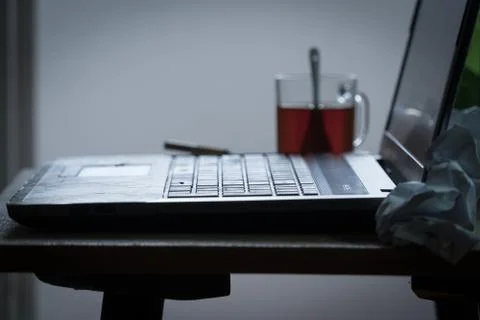 Workplace of a programmer or writer. The laptop is on the table with tea, beer Stock Photos