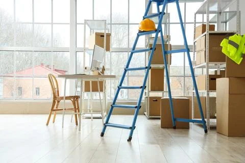 Workplace, stepladder and shelf units with cardboard boxes in warehouse Stock Photos