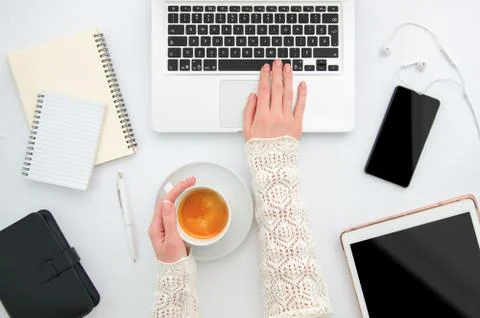 Workplace top view white desktop with gadgets, phone, tablet and female hands Stock Photos