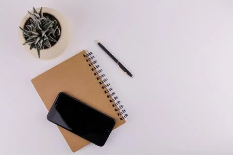 Workplace on white background with notepad smartphone flower and pen Stock Photos