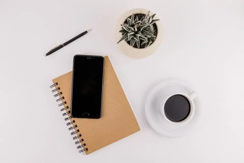 Workplace on white background with notepad smartphone flower and pen and cup  Stock-Fotos