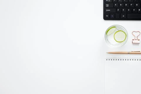 Workplace with white notebook, black keyboard, stationery, glass of water wit Stock Photos