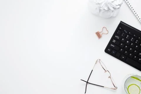 Workplace with white notebook, black keyboard, stationery, glass of water wit Stock Photos