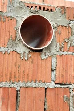 Works on the laying of ceramic bricks. Red brick wall with ventilation hole.  Stock Photos