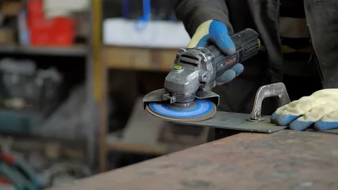 In the workshop. Close-up. The man grinds a metal part with an Angle grinder Stock Footage 128998127