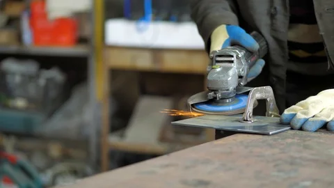 In the workshop. Close-up. The man grinds a metal part with an Angle grinder Stock Footage 128998164