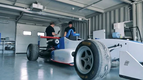 Workshop employees are checking a racing car Stock Footage 165197243