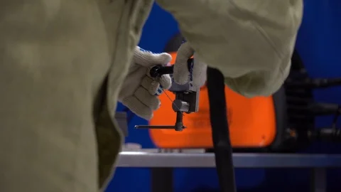 In workshop guy hold semi-automatic and piece of wire, welding unit at factory. Video stock 126356449