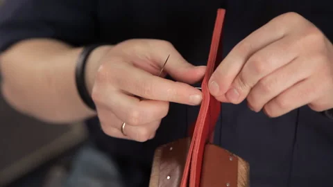 In the workshop, a man is sewing leather workpieces, making a wallet Stock Footage 88839391